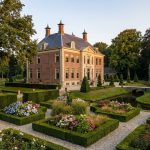 Elegant Nederlands landhuis met klassieke architectuur omringd door uitgebreide formele tuinen met heggen en bloembedden
