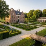 Elegant Nederlands landhuis met klassieke architectuur omringd door uitgebreide formele tuinen en gemanicuurde gazons