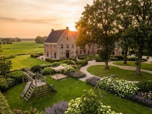 Nederlands landgoed met klassiek landhuis en kindvriendelijke tuin met speeltoestellen tussen bloembedden en gazons