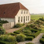 Nederlandse landhuis met crèmekleurige gevel en rode dakpannen, omringd door tuin met goede en slechte ontwerpvoorbeelden