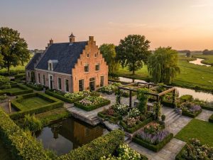Elegant Nederlands landhuis met bakstenen architectuur omringd door uitgebreide tuinen met geometrische hagen en pergola