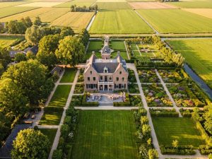 Nederlands landgoed met klassiek landhuis en uitgestrekte tuinen met verschillende oriëntaties in gouden uurtje
